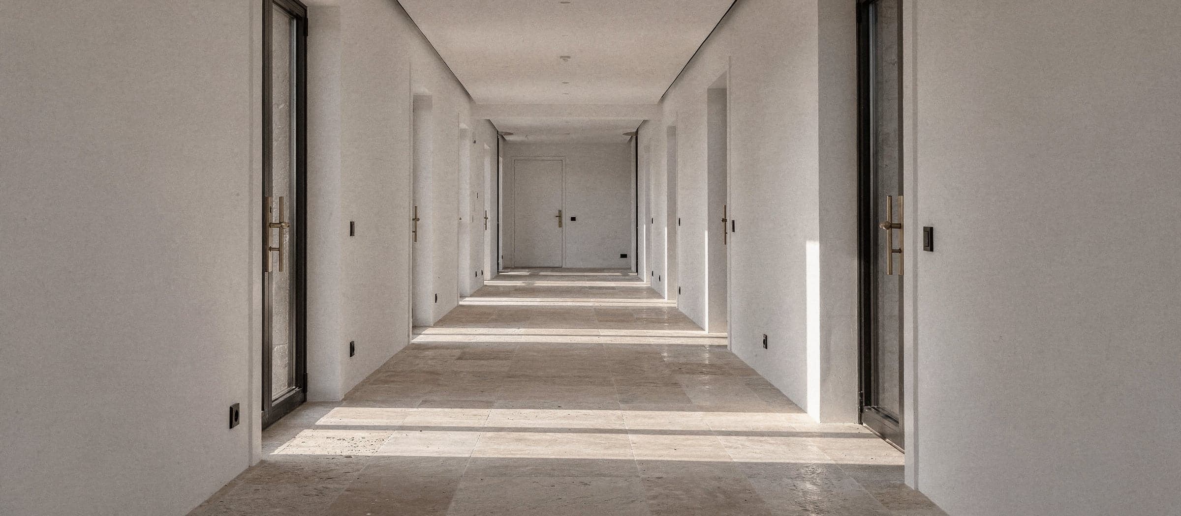 Pasillo de una vivienda nueva con suelo de piedra y luz de tarde